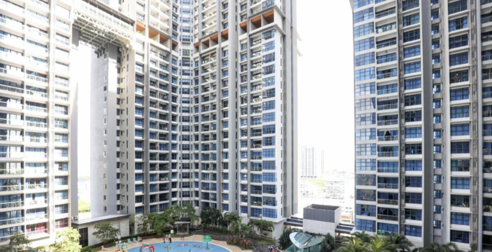 A high-rise residential building with multiple balconies, a rooftop pool, and surrounding greenery.