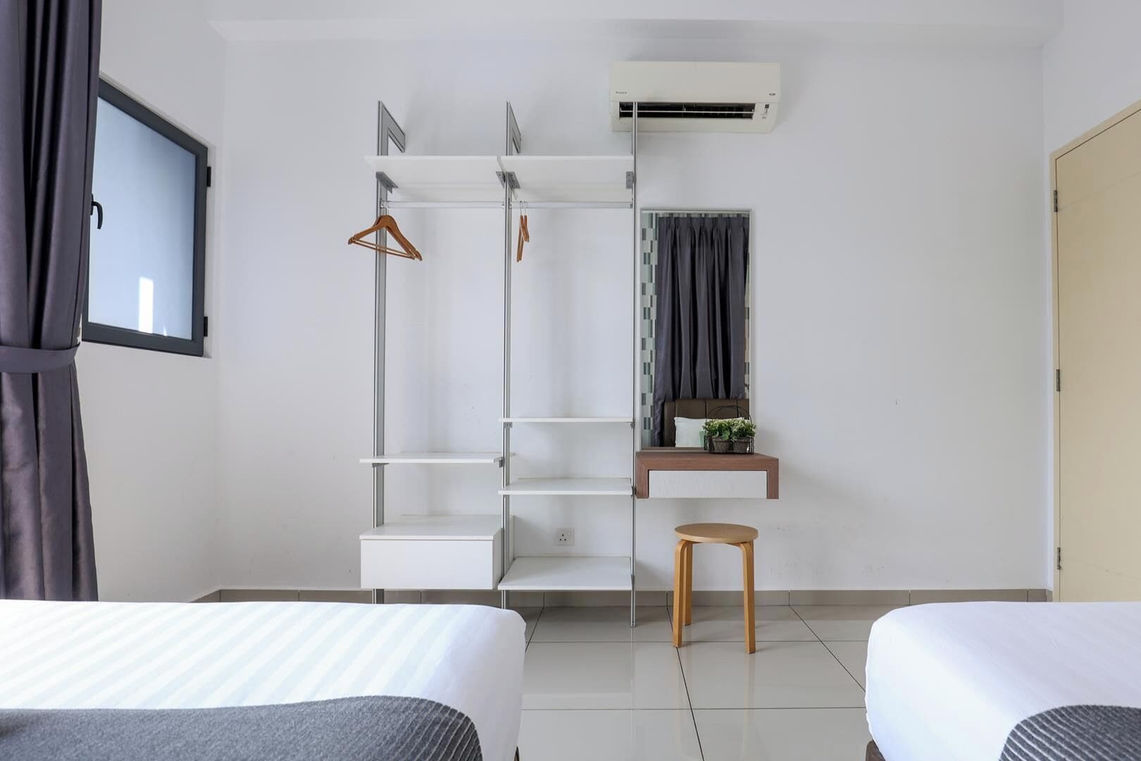 Habitación de hotel con dos camas, un armario, una pequeña mesa con una planta y un equipo de aire acondicionado.