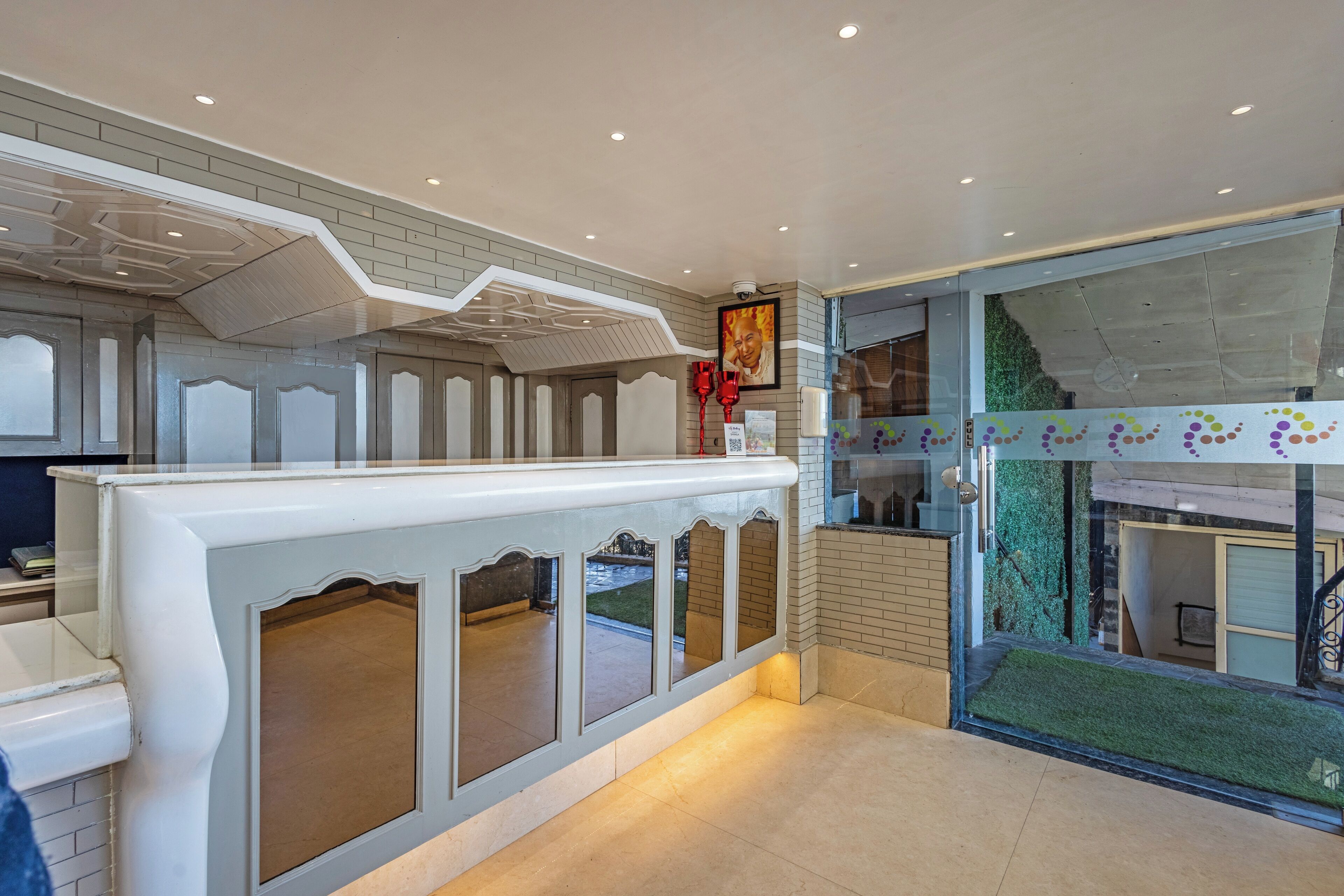 A reception area with a modern design, featuring a counter, glass doors, and a view of the outside.