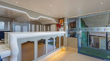 A reception area with a modern design, featuring a counter, glass doors, and a view of the outside.