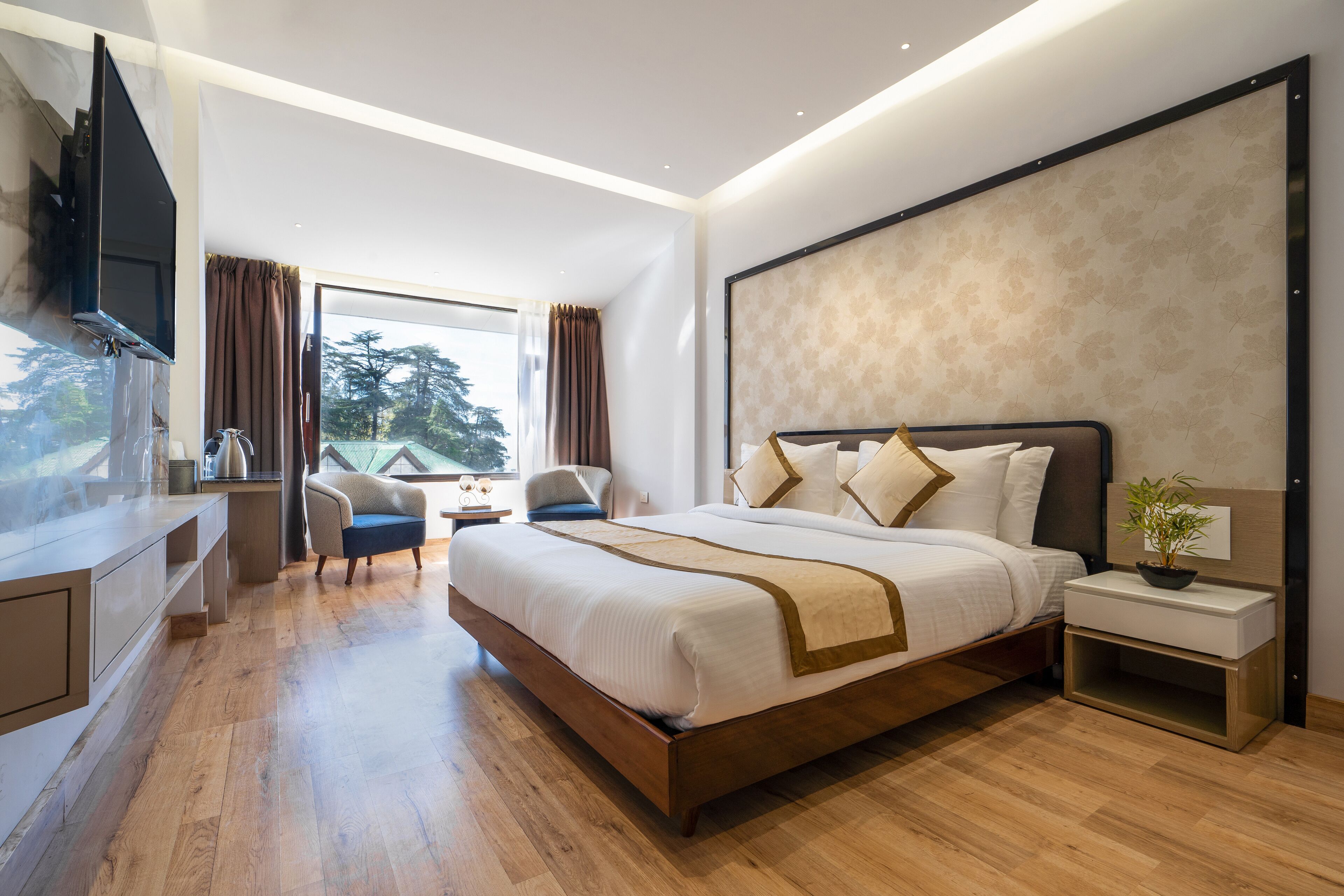 A modern hotel room with a large bed, a desk, a chair, a TV, and a window with curtains.