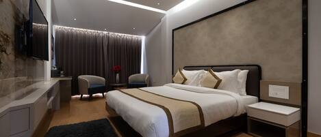 A modern bedroom with a large bed, bedside tables, a TV mounted on the wall, and a desk with a chair.