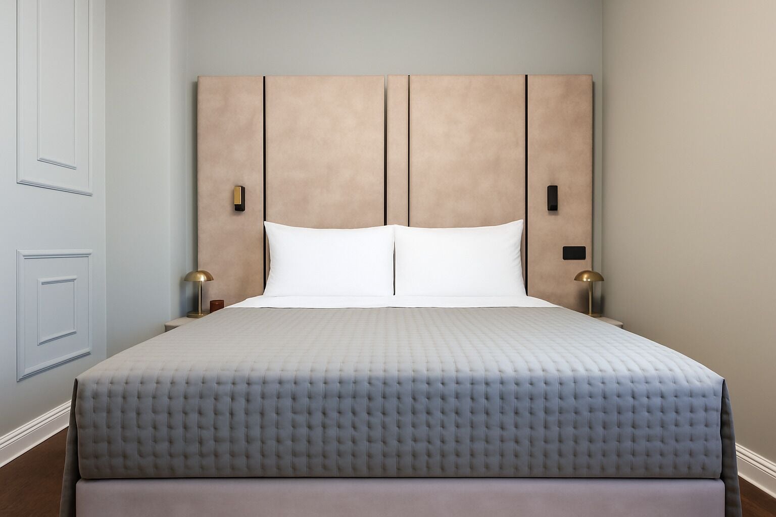 Una cama bien hecha con cabecera capitonada, almohadas blancas y dos lámparas de noche.