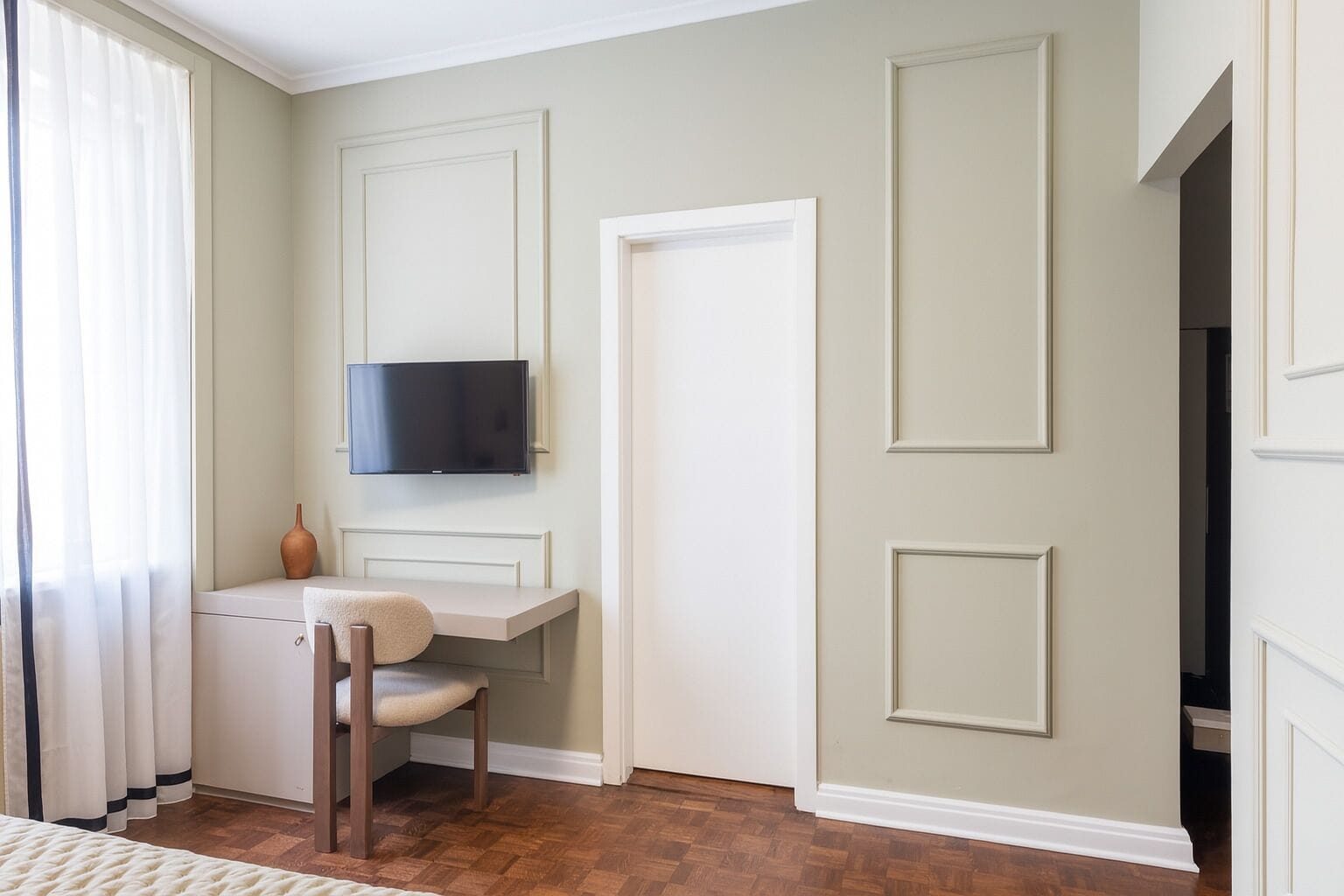 Habitación con escritorio, silla y televisor montado.