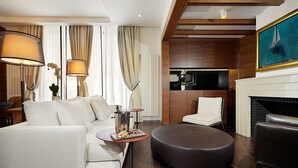 A modern living room with a sofa, ottoman, and chairs, a fireplace, and a TV mounted on the wall. - Hotel Majestic (Belgrade)