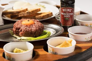 A dining table with a meat dish, bread, and condiments. - Hotel Majestic (Belgrade)