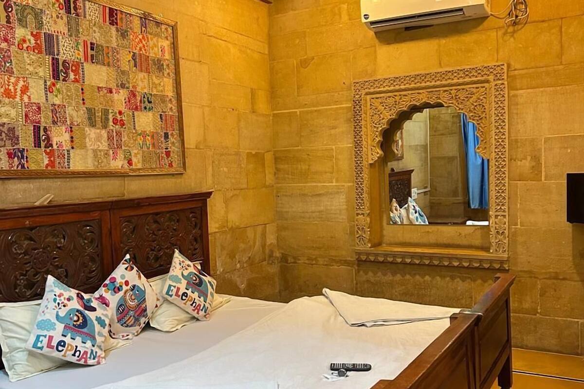 Une chambre avec un lit en bois, un grand miroir décoratif et un climatiseur fixé au mur.
