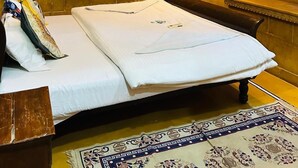A hotel room with a bed, a wall-mounted TV, a decorative mirror, and a patterned rug. - Hotel Pol Haveli (Jaisalmer)