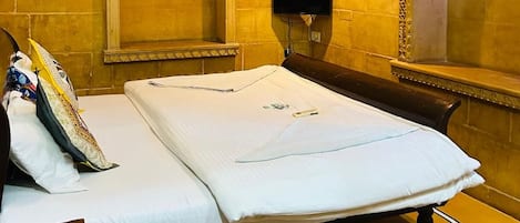 Una habitación de hotel con una cama, un televisor de pared, un espejo decorativo y una alfombra estampada.