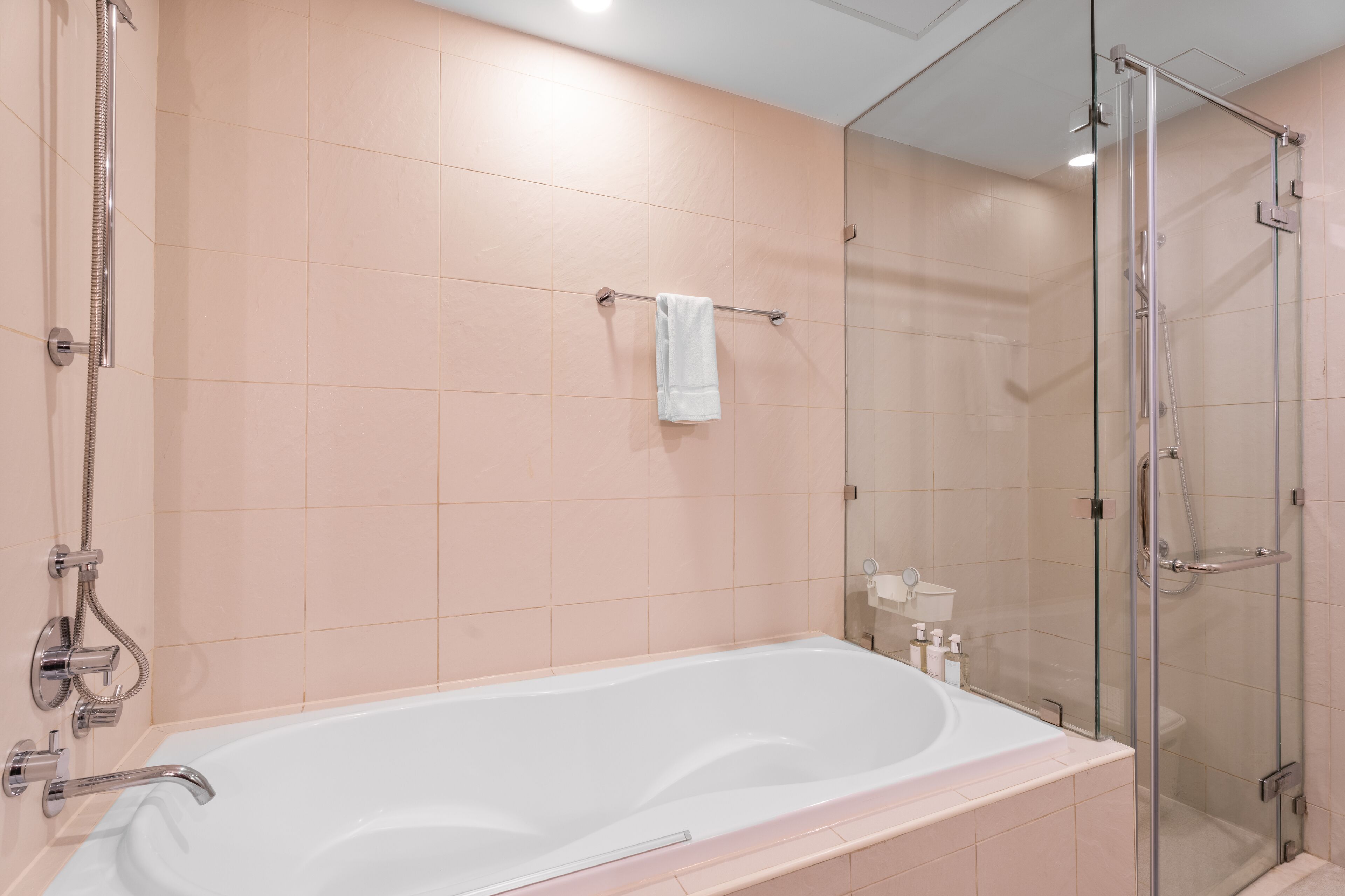 A modern bathroom with a large bathtub, a glass shower enclosure, and a towel rack with a single towel.