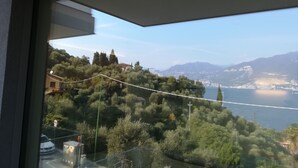 A balcony with a view of a lake, trees, and distant mountains. - Hotel San Marco (Torri del Benaco)