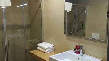 Une salle de bain moderne avec une douche à parois de verre, un lavabo blanc et un miroir au-dessus.