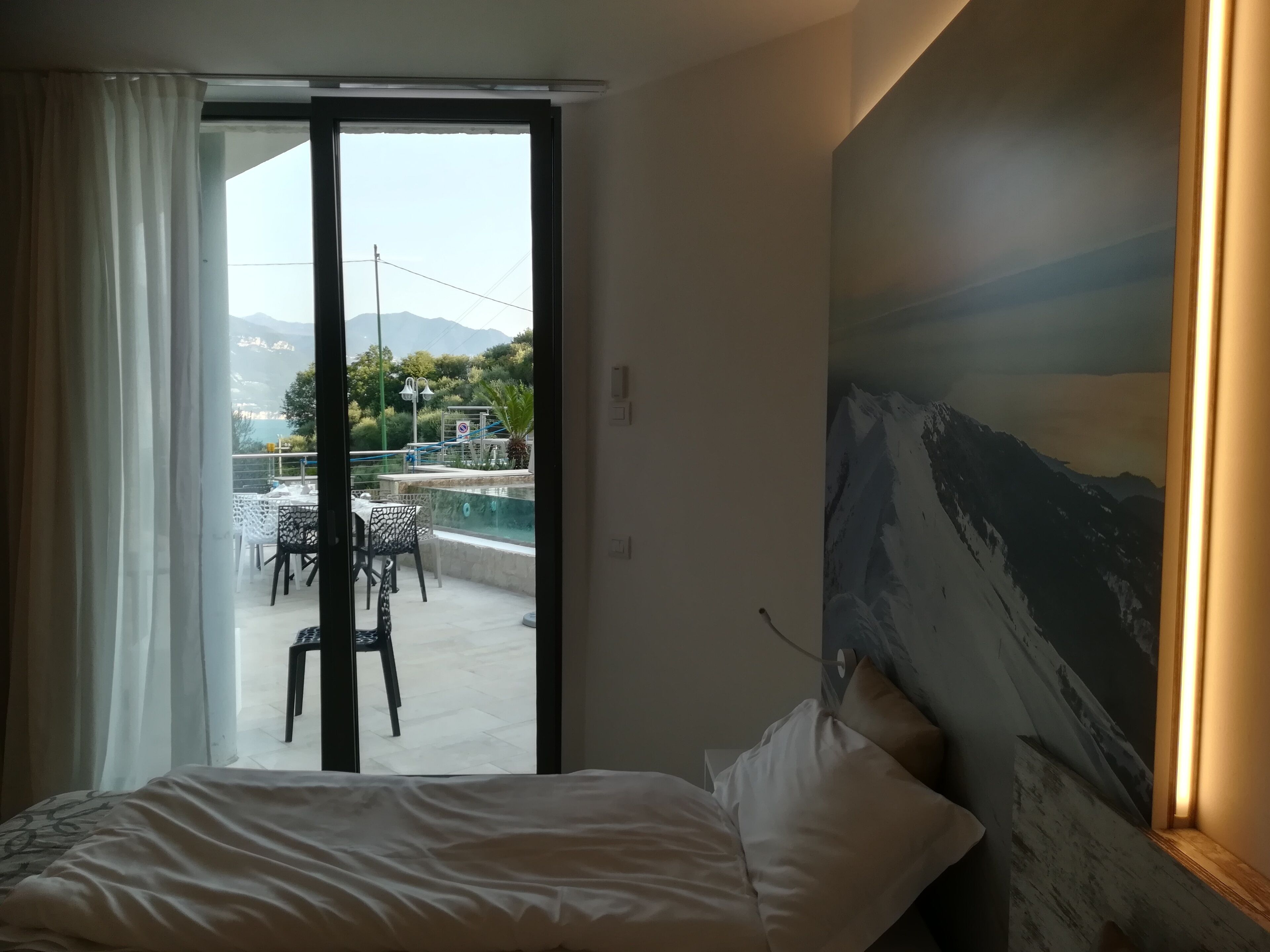 Une chambre d’hôtel avec un lit, un tableau et une vue sur une piscine extérieure et un espace patio.