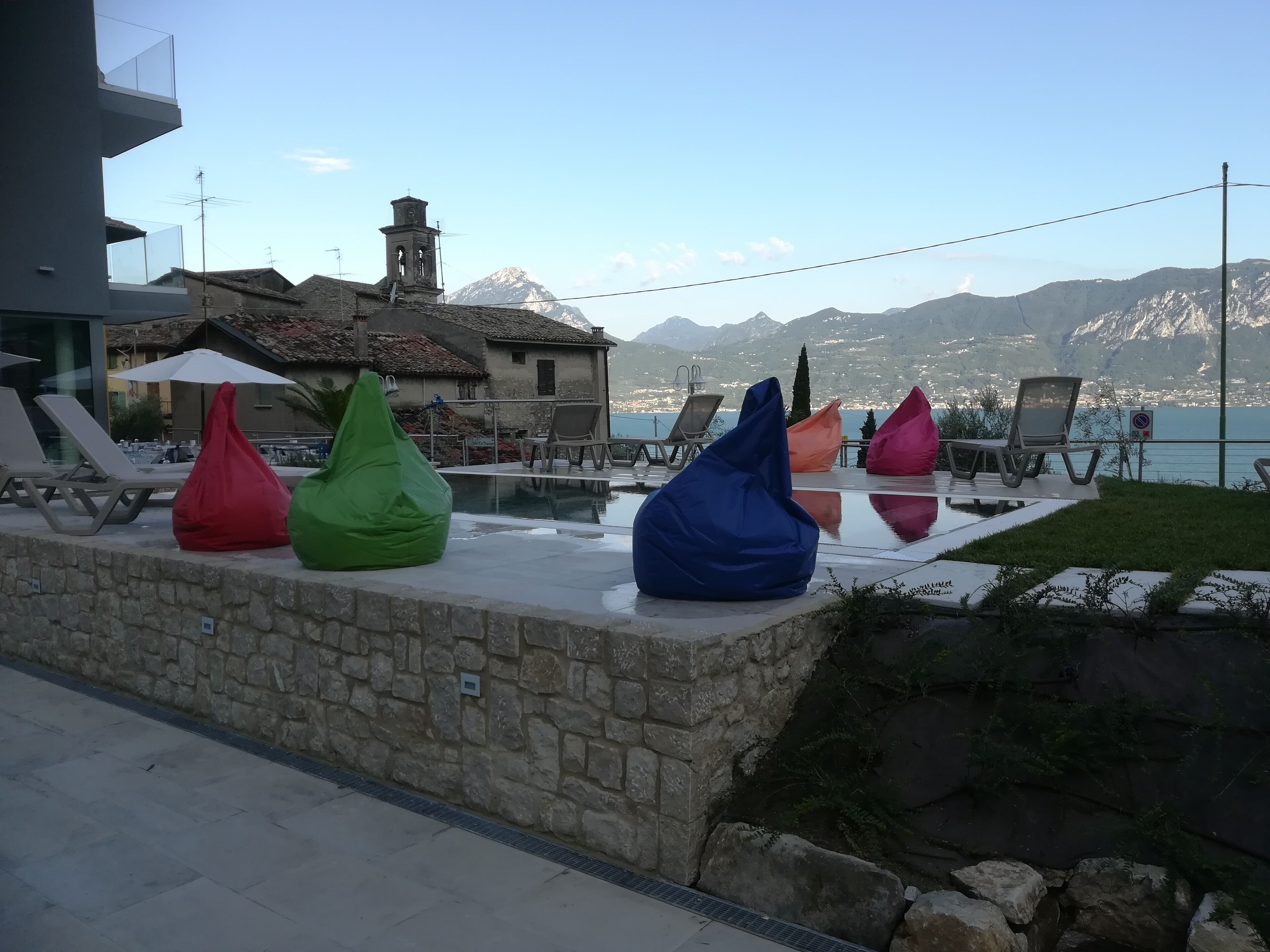 A poolside area with lounge chairs and bean bags, overlooking a mountainous landscape.