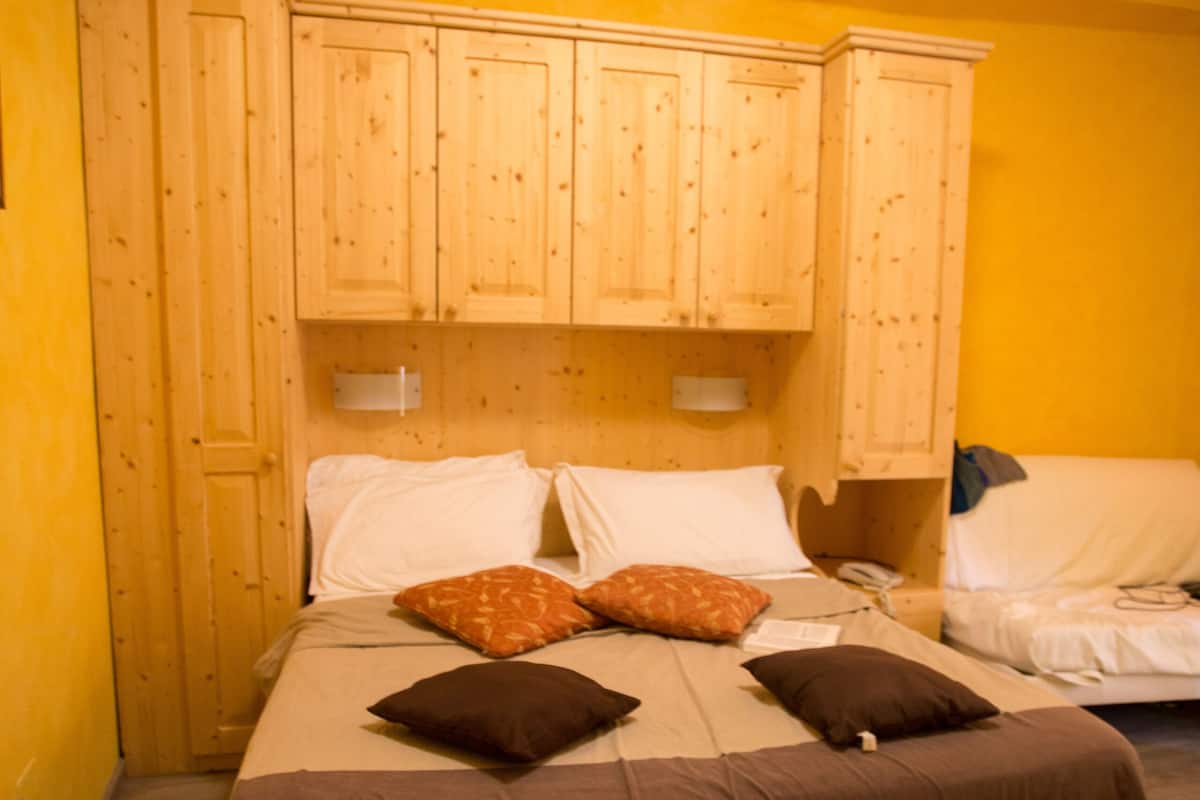 Ein Schlafzimmer mit einem Doppelbett, Holzschränken und einem Nachttisch.
