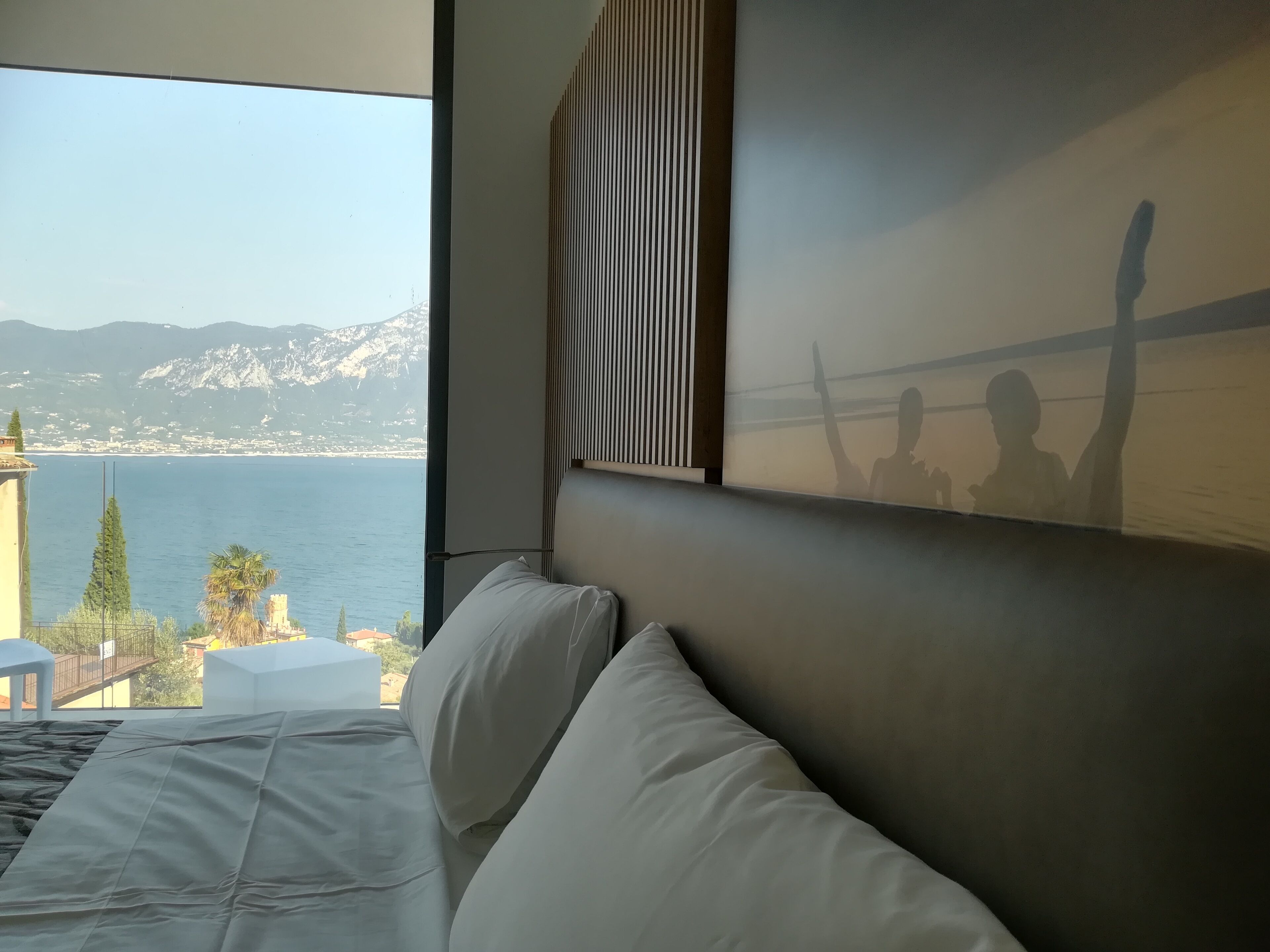Habitación de hotel con una cama grande, vista al mar y una montaña al fondo.