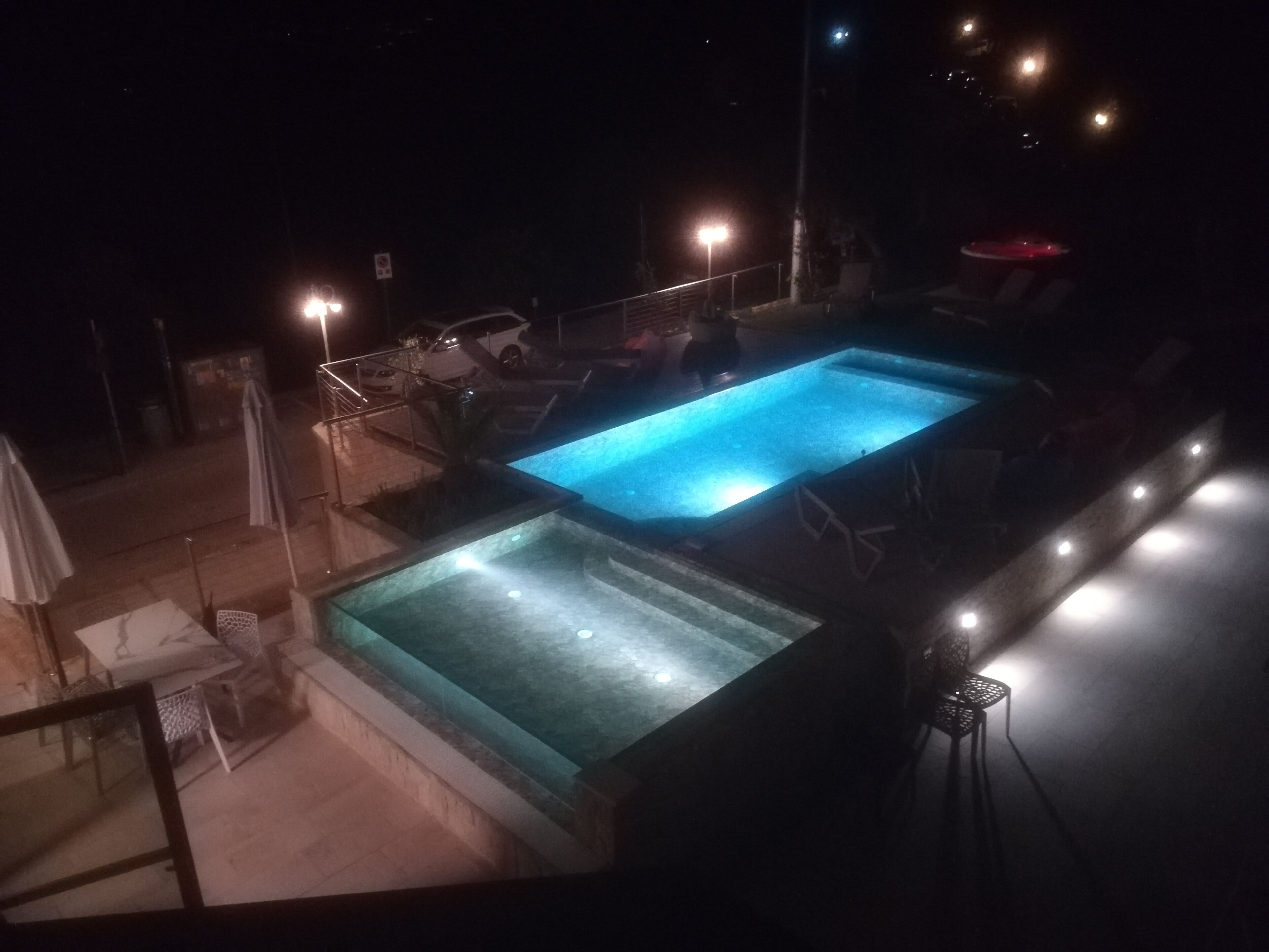 Tagpool med to swimmingpools, liggestole og parasoller.