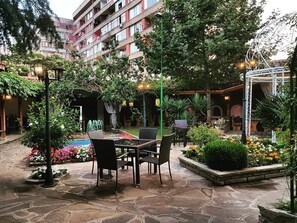 Un espace extérieur aménagé en terrasse, avec un sol en pierre, des sièges et une végétation luxuriante.