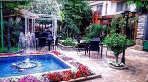 Une cour avec une fontaine, des sièges extérieurs et un jardin.