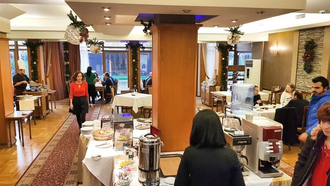 Un restaurante con mesas dispuestas para comer, una máquina de café y un dispensador de agua.