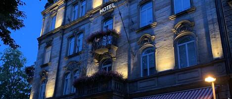 Een hotel met een klassiek gevelontwerp, grote rondboogvensters en een bord met de vermelding dat het een hotel is.