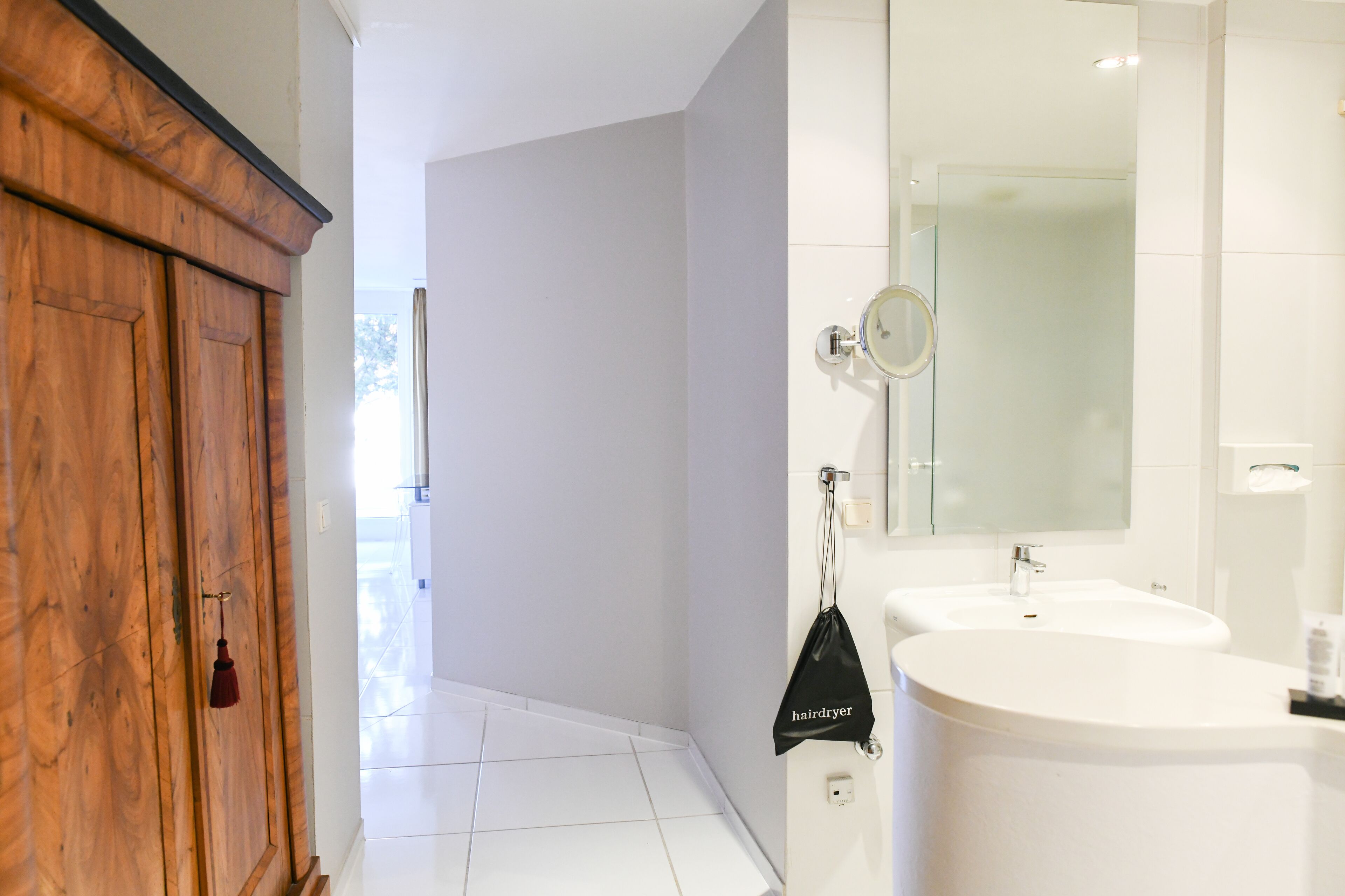 A modern bathroom with two sinks, a large mirror, and a wooden cabinet.