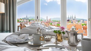 A neatly arranged breakfast table with a view of a historic cityscape through large windows.