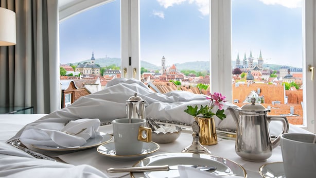 A neatly arranged breakfast table with a view of a historic cityscape through large windows.