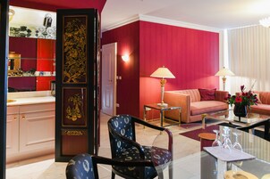 Una sala de estar moderna con una pared de acento roja, un sofá, una mesa de centro y un sillón decorativo.