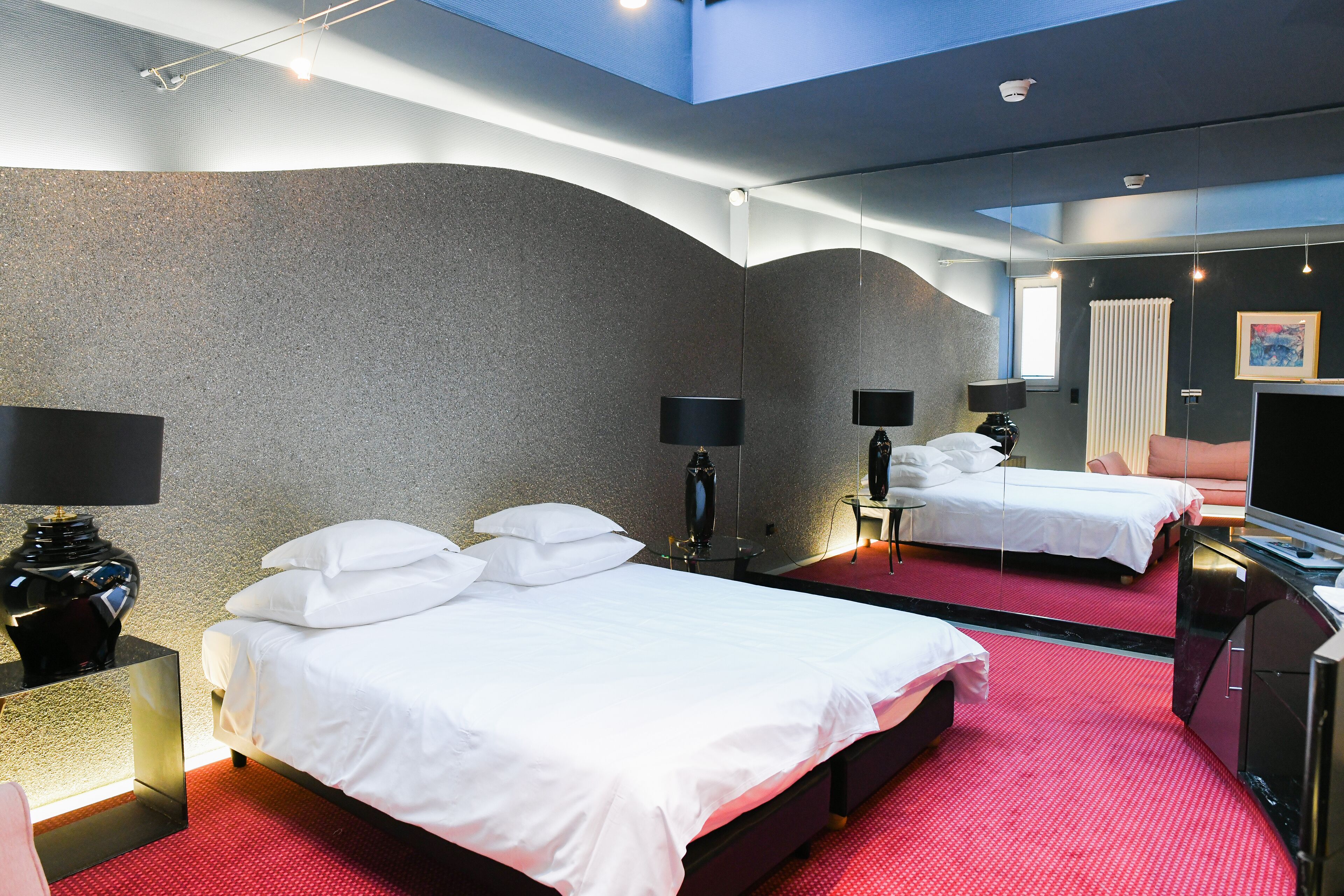 A hotel room with two beds, a TV, and a large mirror.