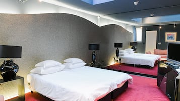 A hotel room with two beds, a TV, and a large mirror.