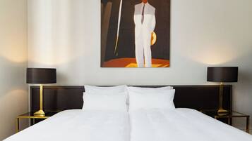 A hotel room with a large bed, two bedside tables with lamps, and a painting on the wall.