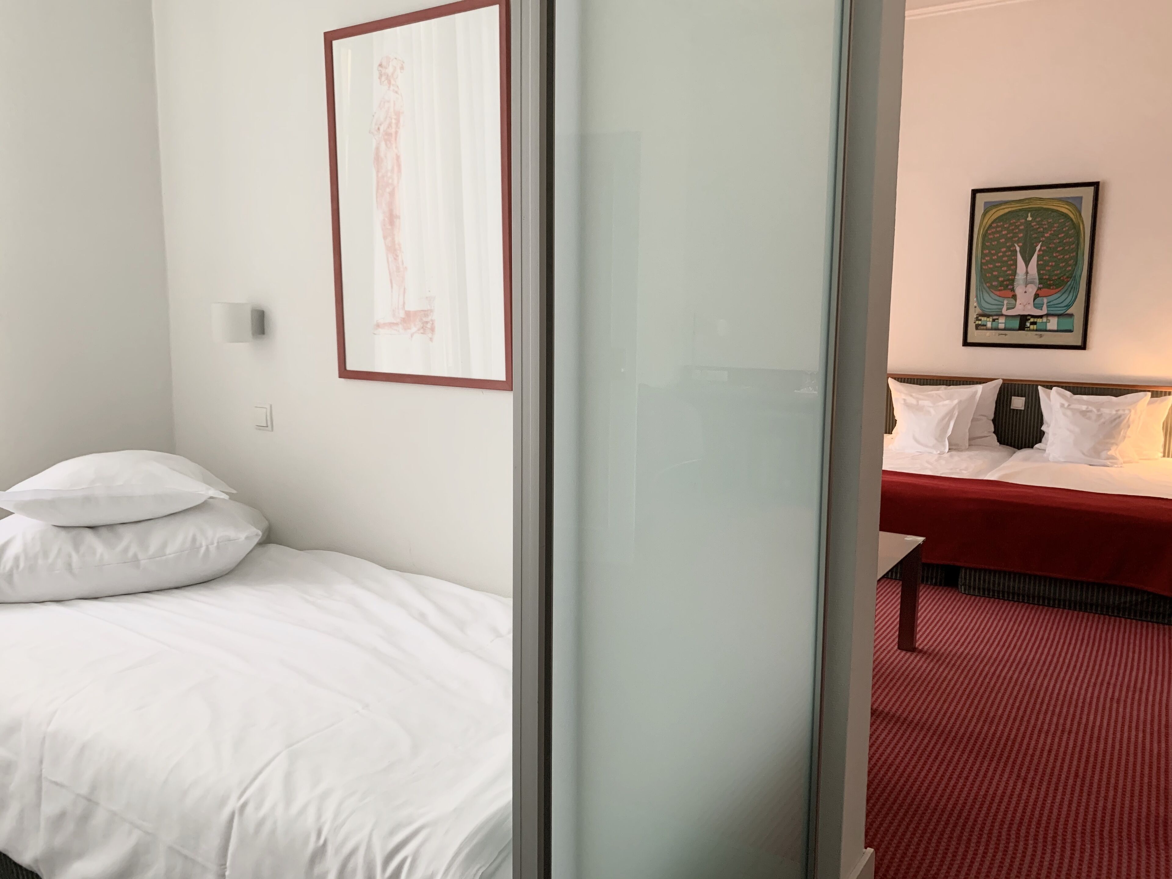 Habitación de hotel con una cama, una mesita de noche y una alfombra roja.