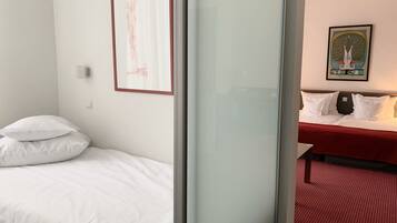 Habitación de hotel con una cama, una mesita de noche y una alfombra roja.