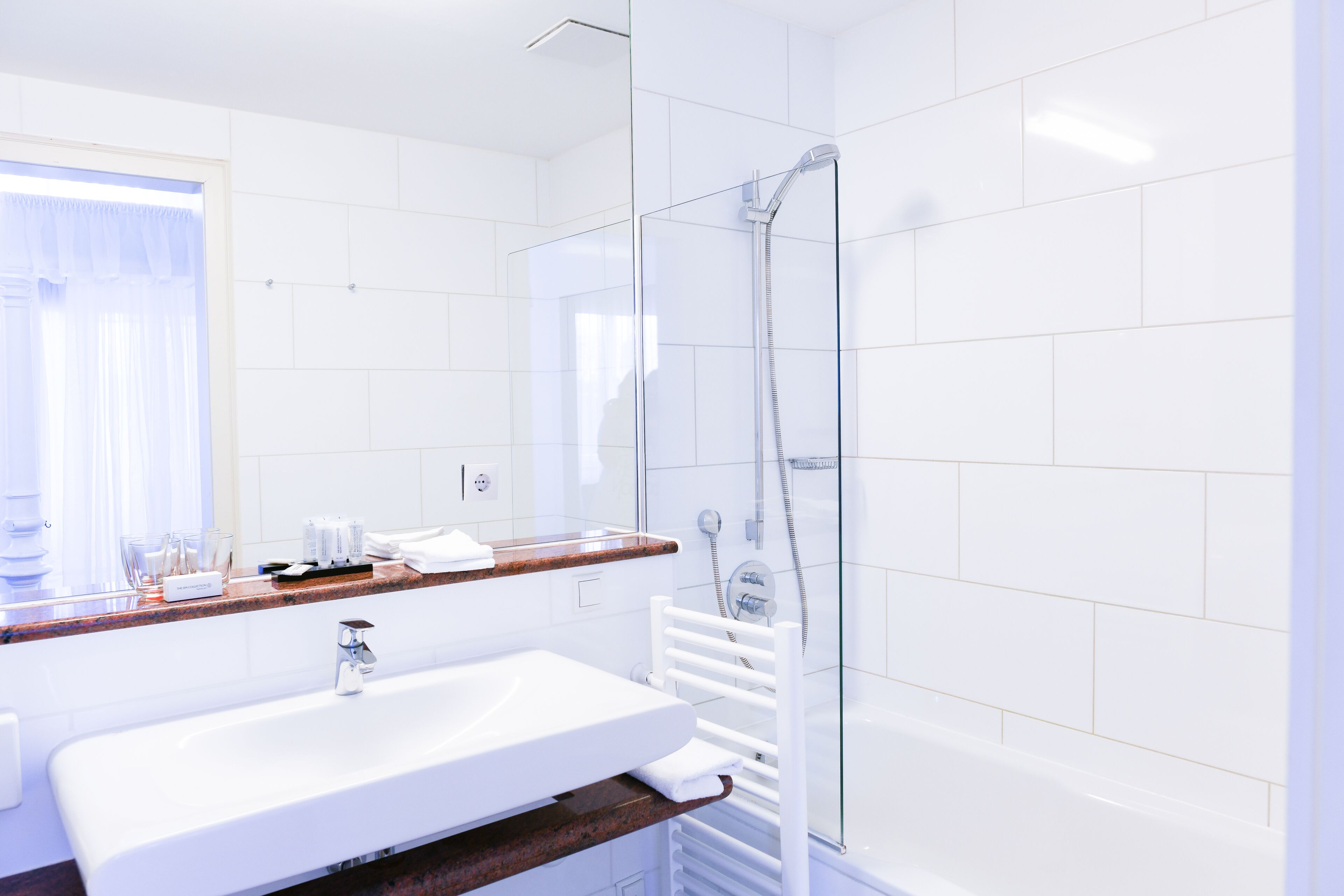 A modern bathroom with a glass-enclosed shower, a white sink, and a marble countertop.