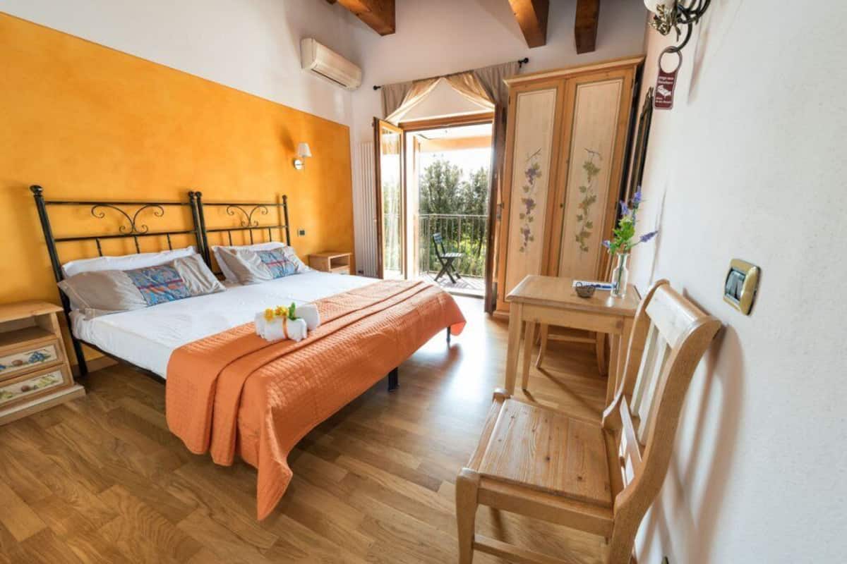 Un dormitorio con cama, piso de madera, un escritorio y una silla.