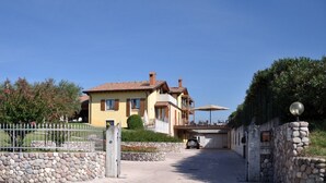 Una villa amarilla con techo de tejas, pared de piedra y camino empedrado que lleva a una entrada.