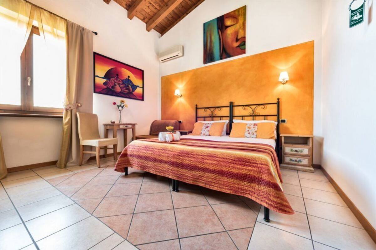 Un dormitorio con cama, una silla, una mesita y una lámpara de pared.