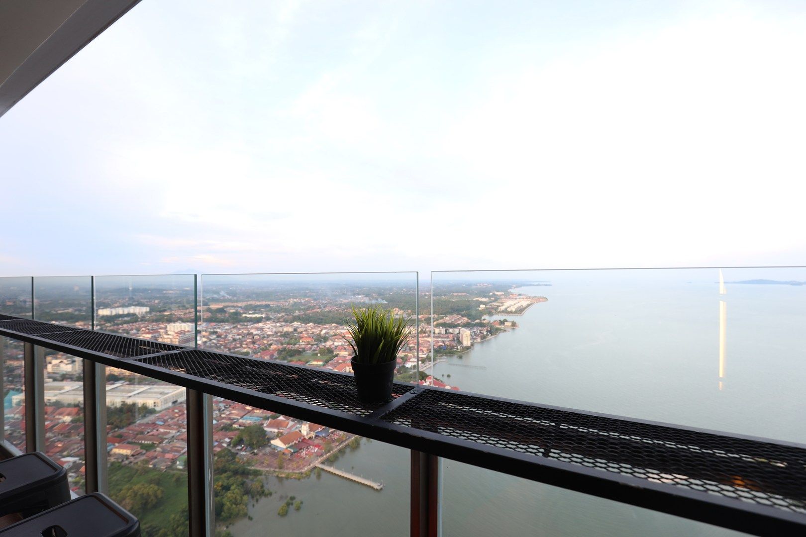 En balkong med ett metallräcke som vetter ut mot en stadsbild och en vattenyta.