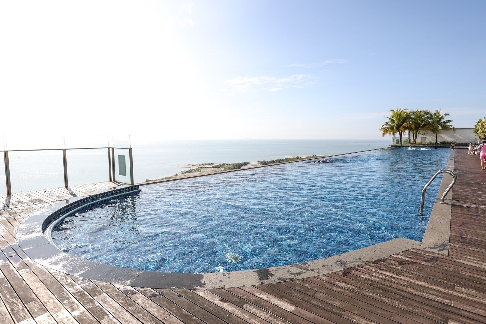 A swimming pool with a wooden deck and a view of the ocean.