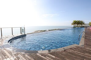 Ein Schwimmbecken mit einer Holzterrasse und Blick auf den Ozean.