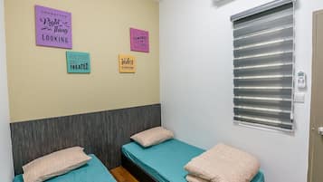 A room with two beds, a wall-mounted air conditioner, and motivational posters.