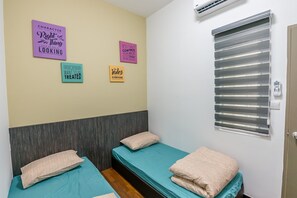 Habitació amb dos llits, aire condicionat fixat a la paret i pòsters motivacionals.
