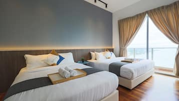 A hotel room with two beds, a large window with curtains, a wooden floor, and a nightstand with a plant.