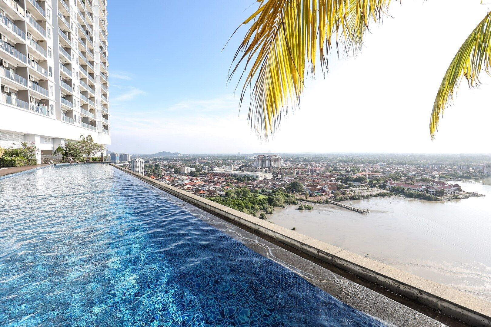 An infinity pool with a view of a cityscape and a river.