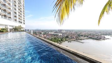 An infinity pool with a view of a cityscape and a river.