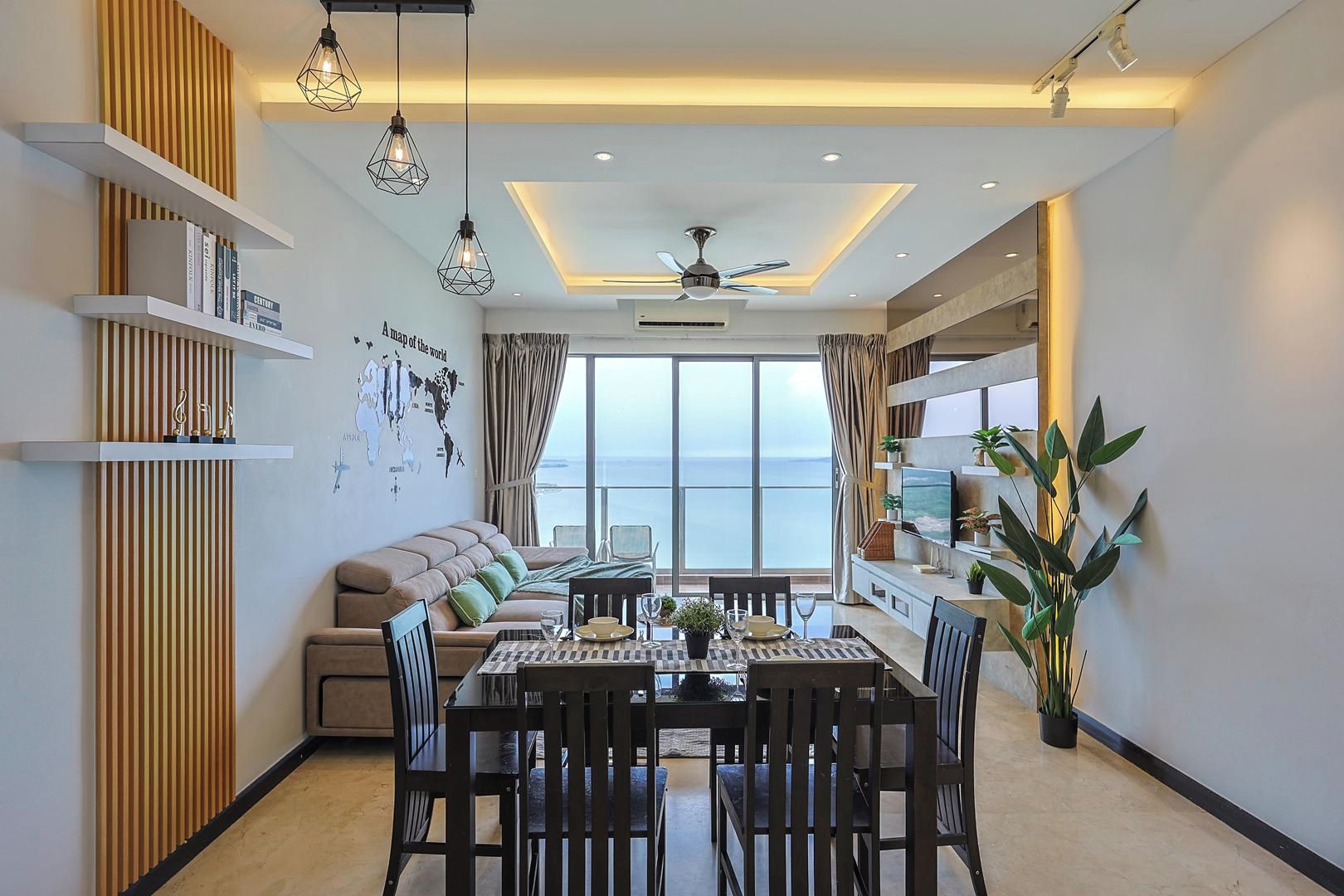 A modern living room with a sofa, dining table, and chairs, a large window with a view, and decorative wall shelves.
