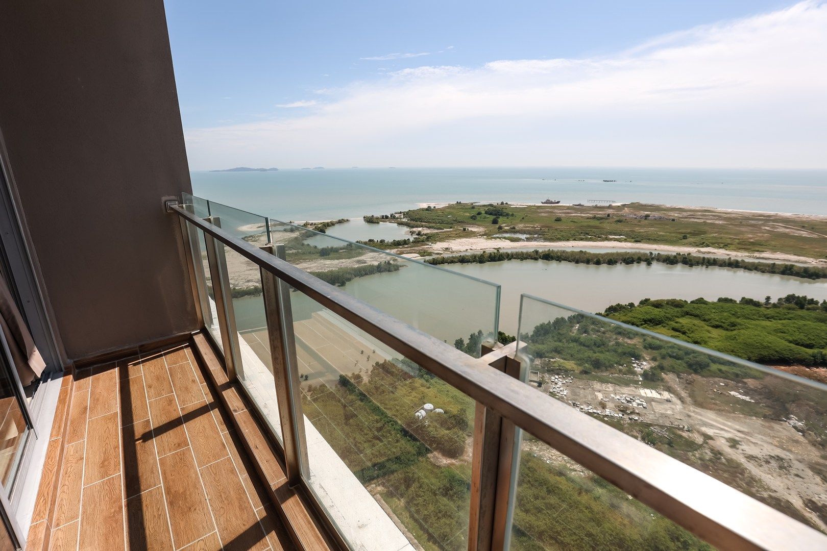 Een balkon met uitzicht op een kustlandschap, inclusief een waterpartij en verre eilanden.