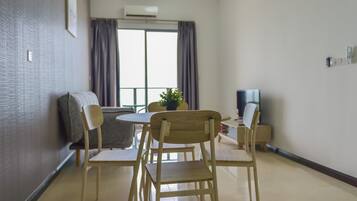 Un salon moderne comprenant une table à manger, des chaises, un canapé, un téléviseur et une grande fenêtre avec des rideaux.
