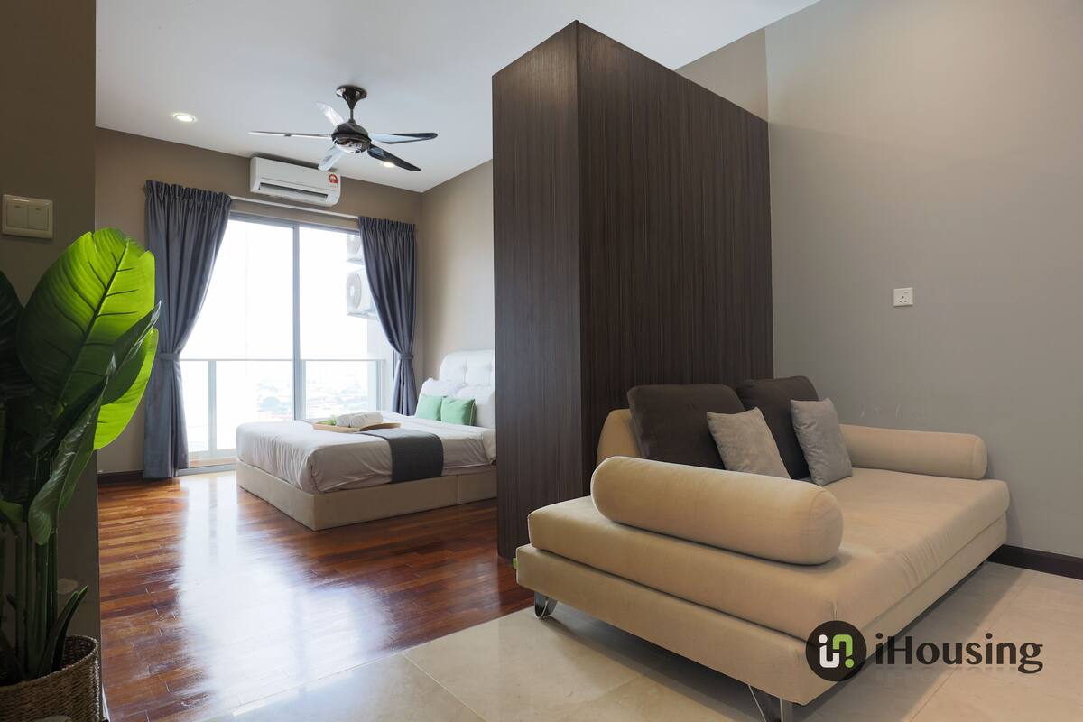 A modern living room with a sofa, a bed, and a large plant.